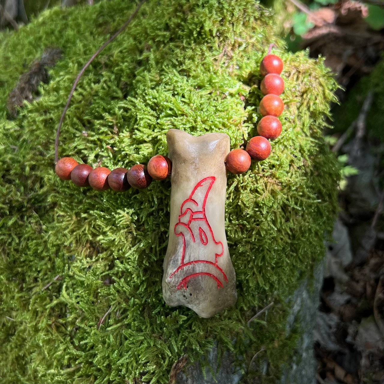 Collana con falange di alce con drago norreno inciso e dipinto